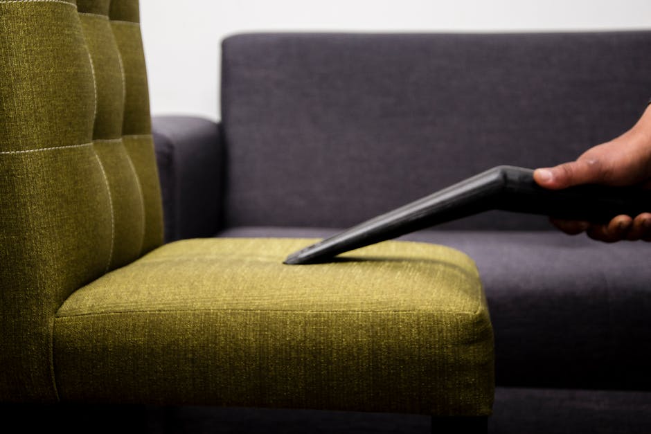 A pristine white upholstered sofa with tufted back and rolled arms, situated in a room with white paneled walls and wooden flooring. The sofa surface appears clean and well-maintained, reflecting a de
